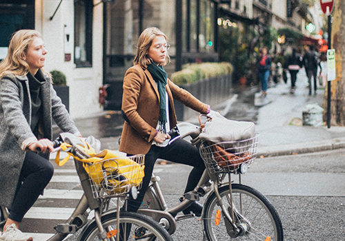 15 Minuten Stadt zwei Damen am Fahrrad im Hintergrund eine Straßenansicht